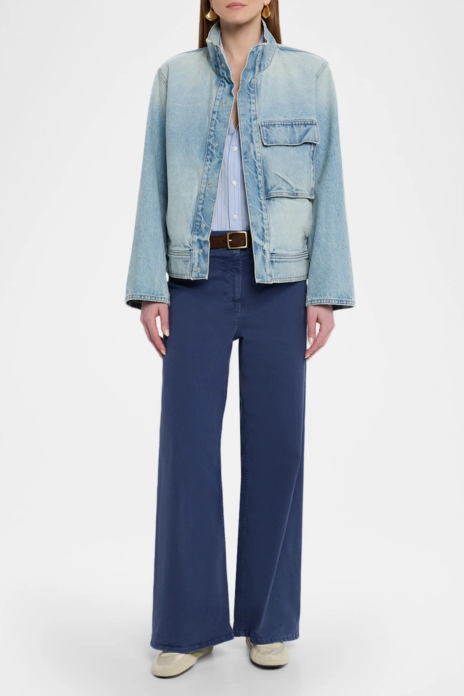 Person wearing a light blue denim jacket and dark blue pants on a white background